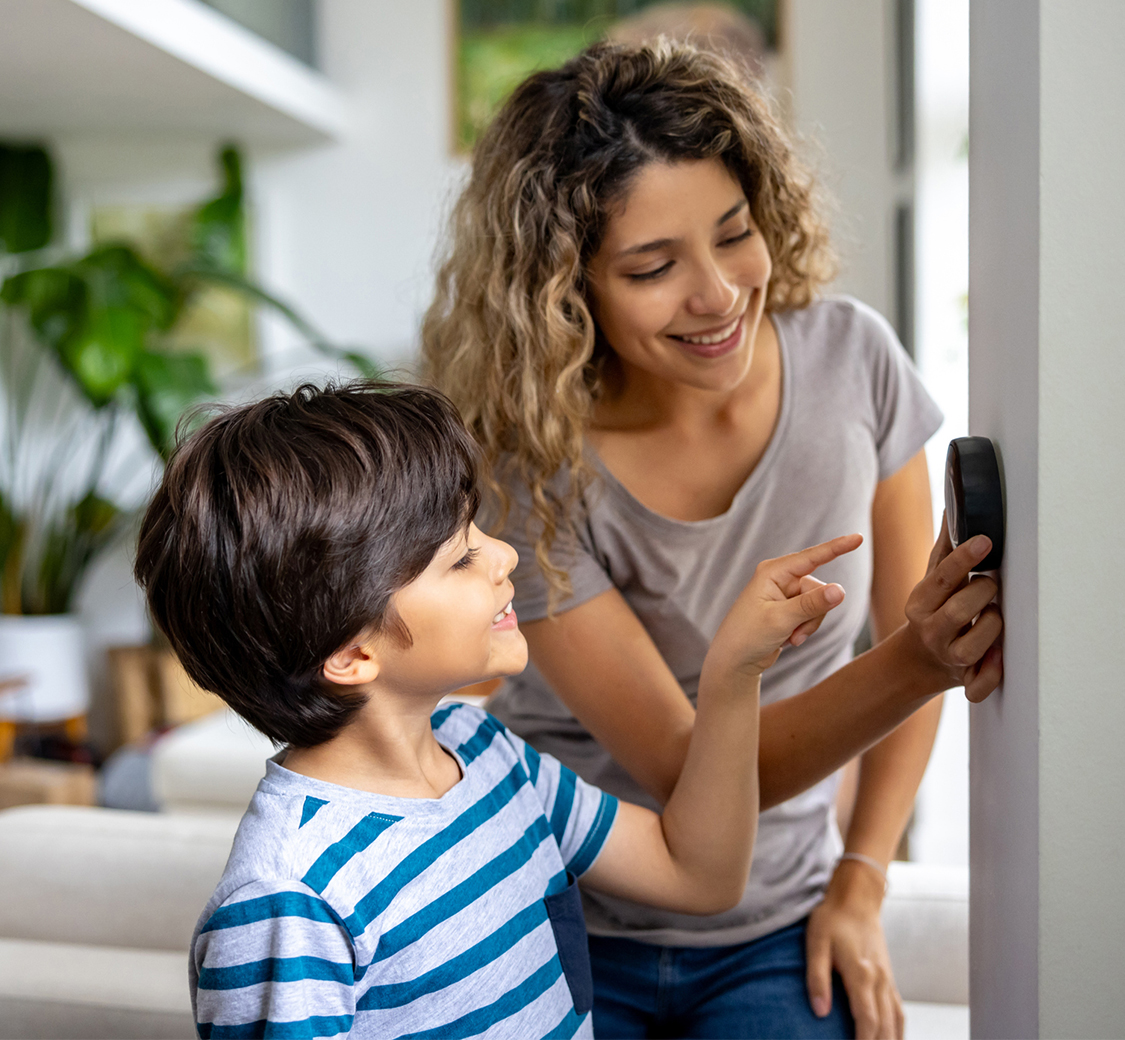 Mother and child adjusting the thermostat